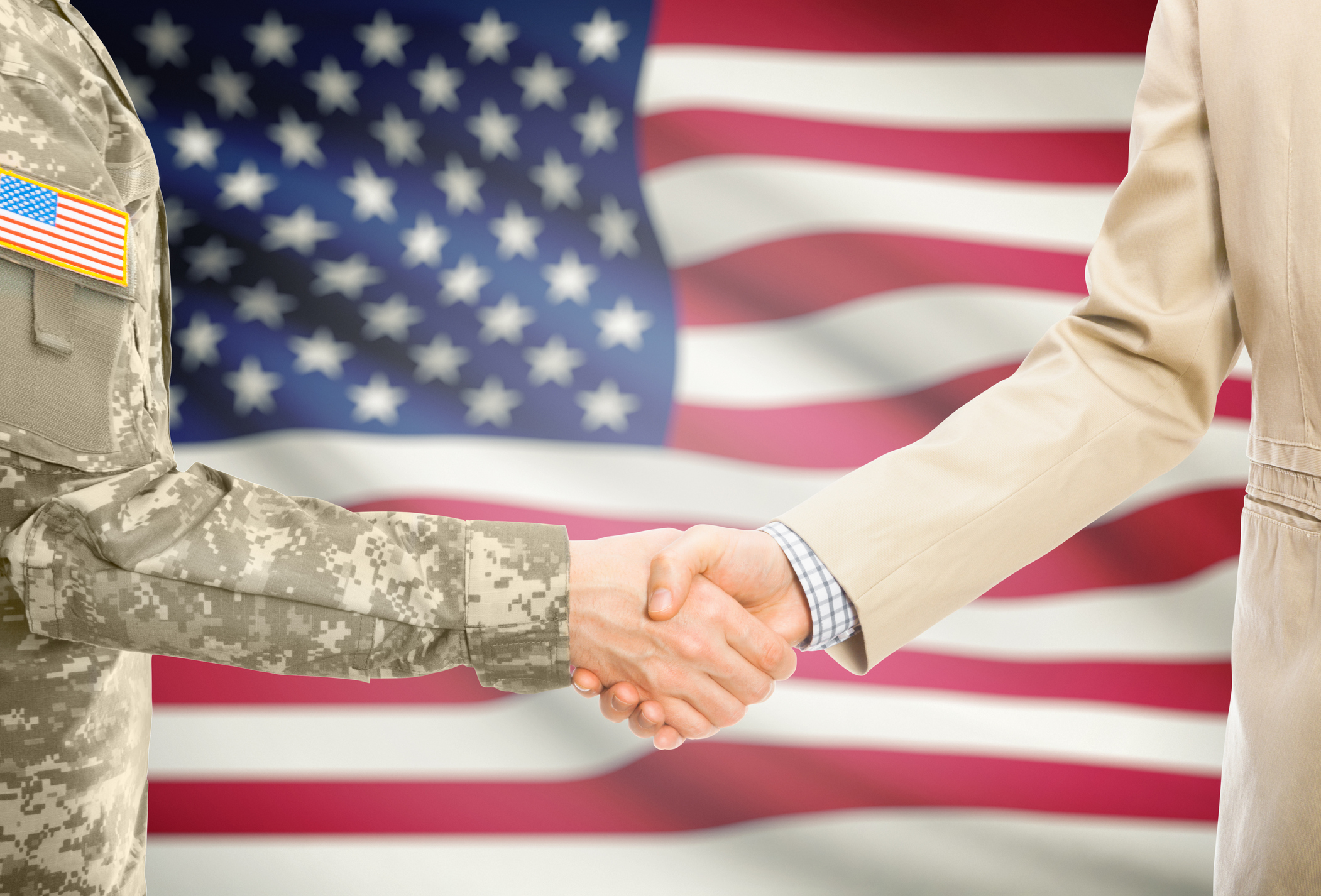 USA military man in uniform and civil man in suit shaking hands with national flag on background - United States